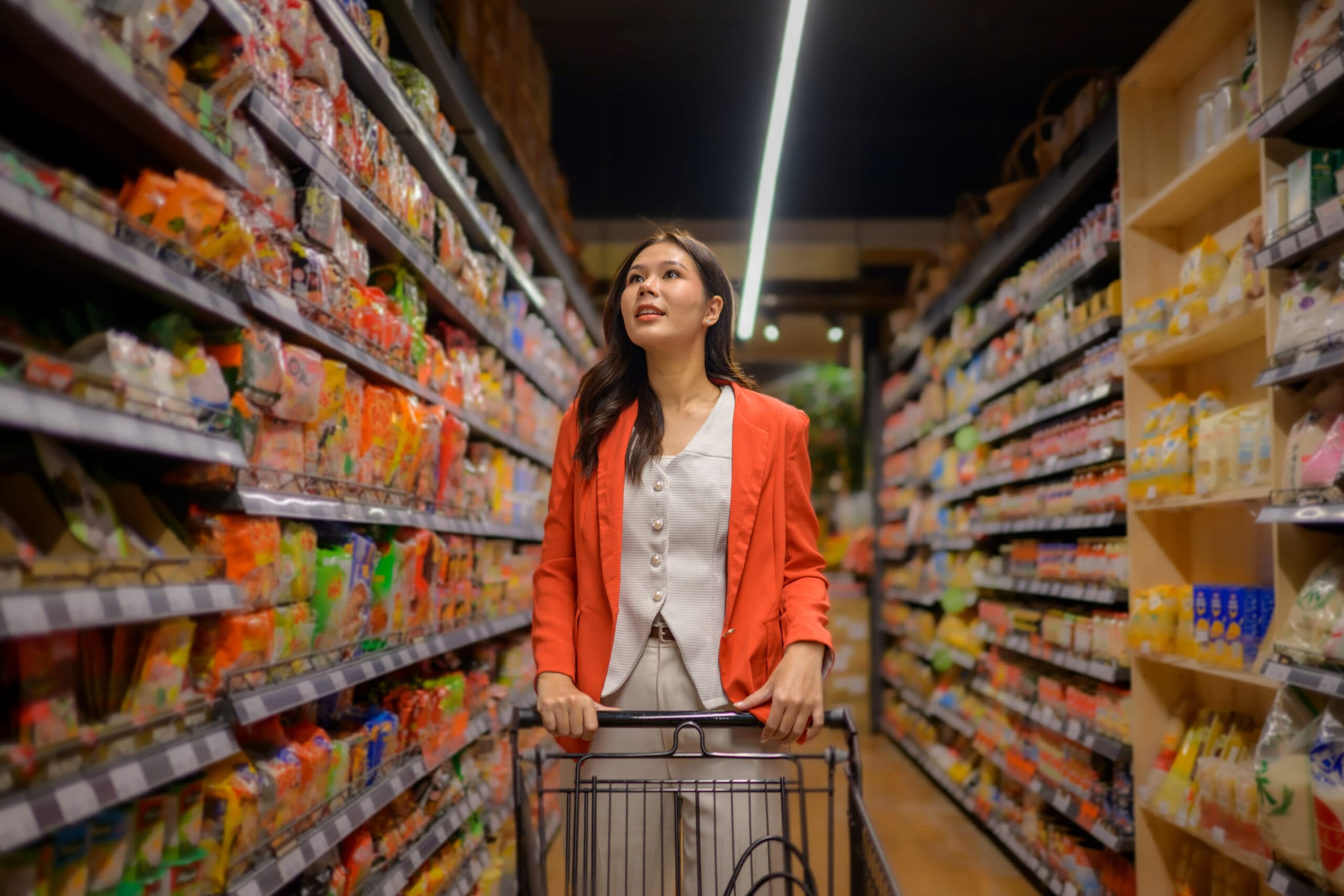 Shopper in a grocery aisle looking up while listening to an in-store message